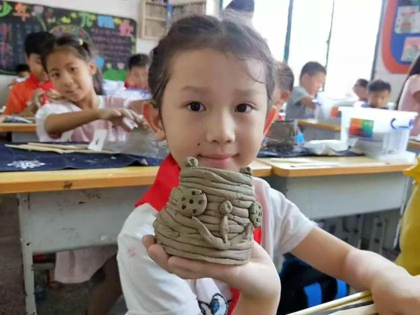 学生在校园非遗课堂展示亲手完成的陶艺作品