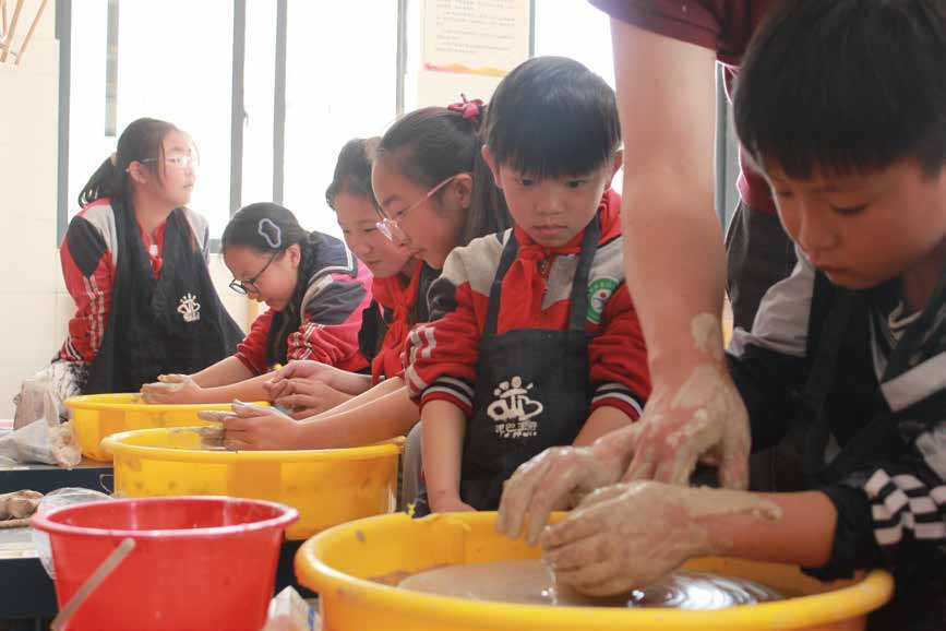 学生在老师指导下使用拉坯机体验陶艺制作